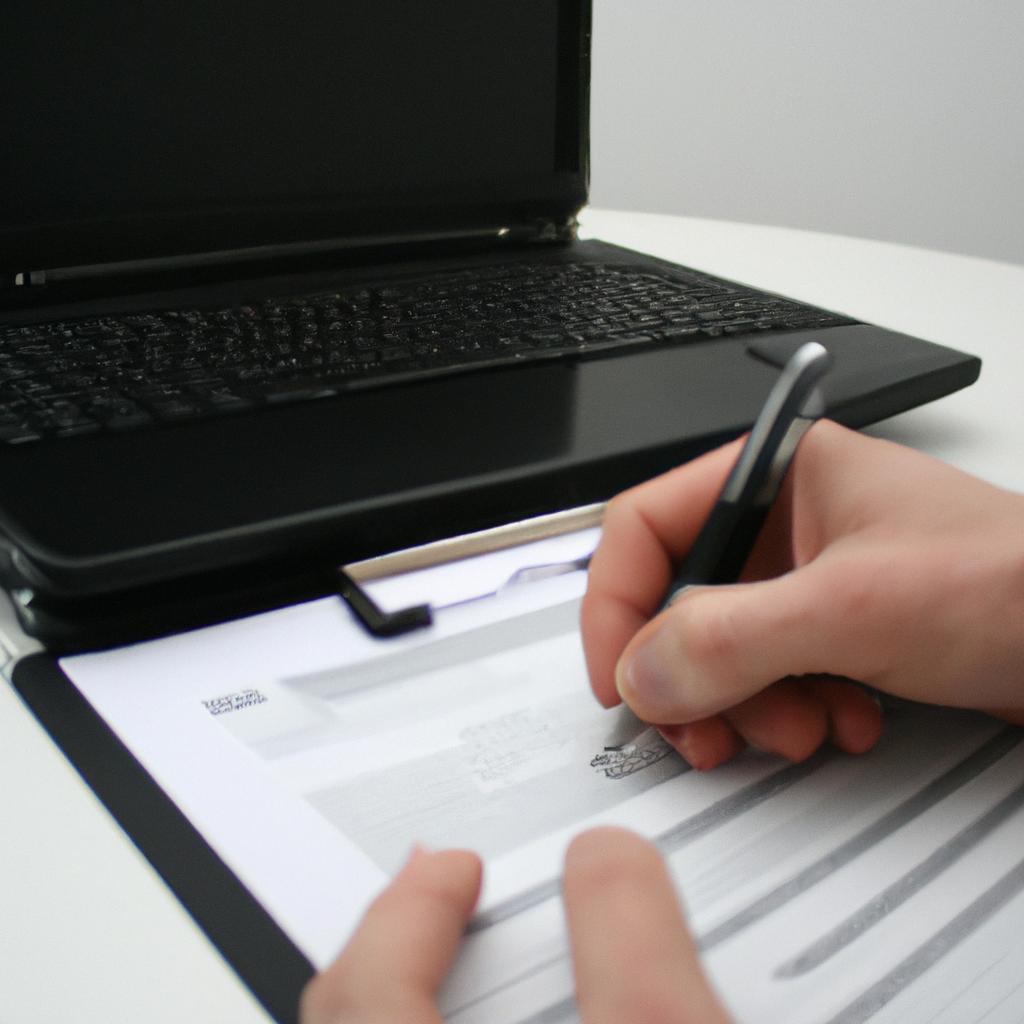 Person holding laptop, signing documents
